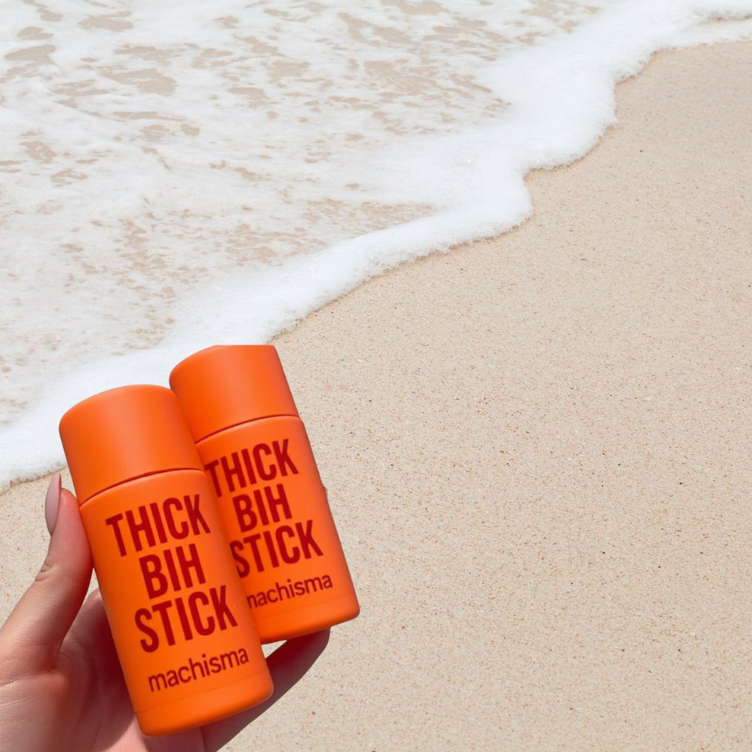 Hand holding orange Thick Bih Sticks at the beach